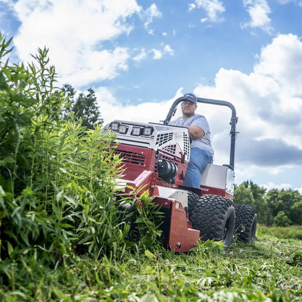 A North Star Grounds Care crew member operating a Ventrac tractor through tall brush
